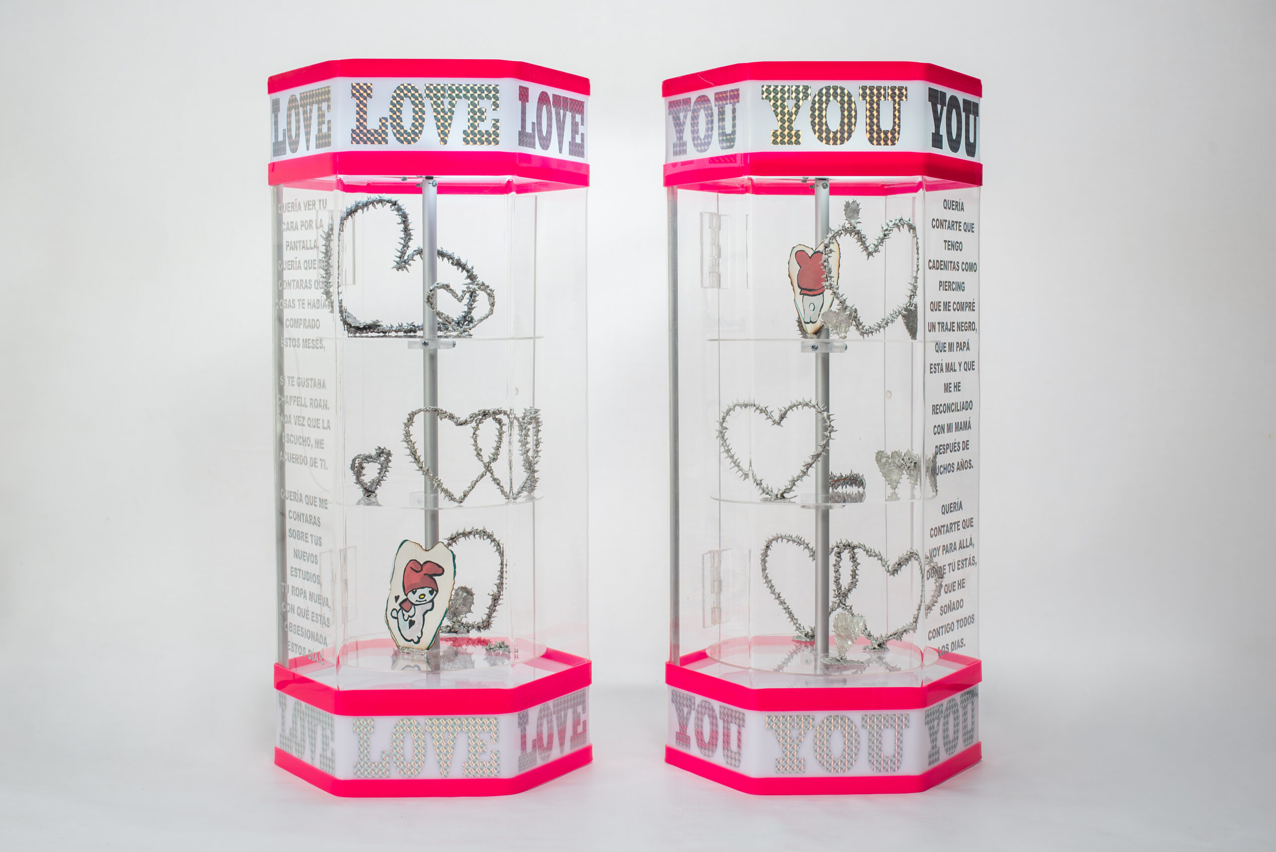 Marisabel Arias. Love (long distance) You (long distance), 2025. Acrylic showcases, rotating bases, lights, tin, copper and silver brazing, vynil text, gouache on cotton paper, 62 x 27 x 27 cm. each