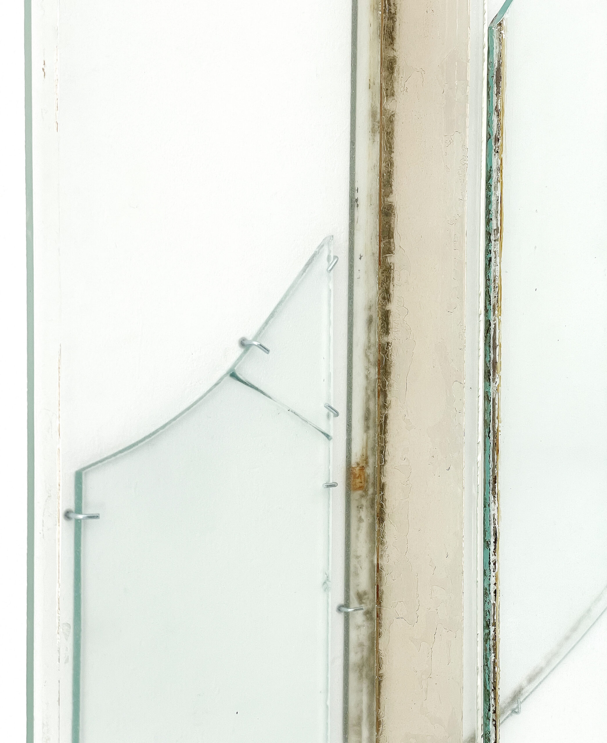Anneke Eussen, Planning the past 01, 2025, car pane, recycled glass, coloured glass, metal hooks, mounted to the wall, 147 x 75 cm, unique