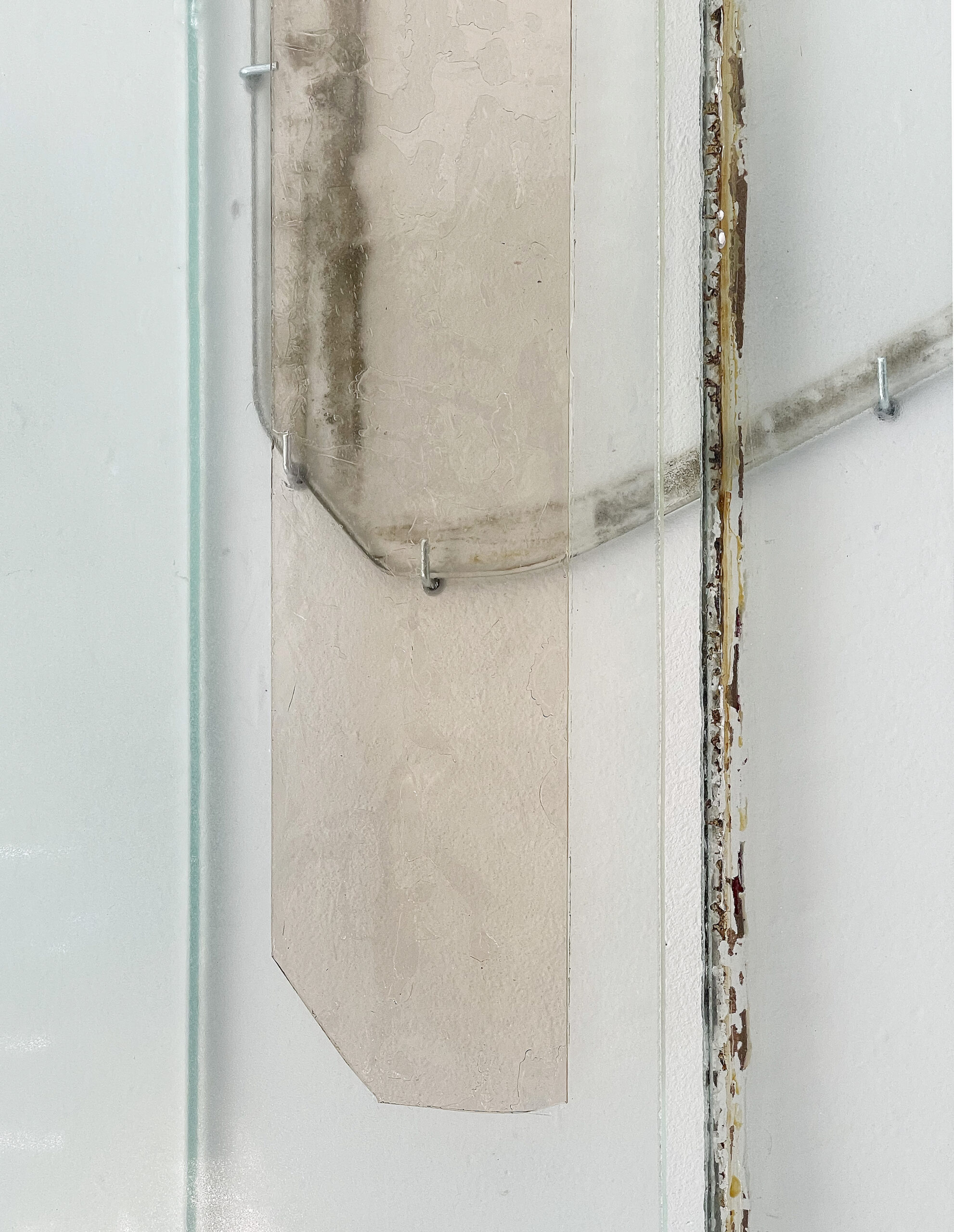 Anneke Eussen, Planning the past 01, 2025, car pane, recycled glass, coloured glass, metal hooks, mounted to the wall, 147 x 75 cm, unique